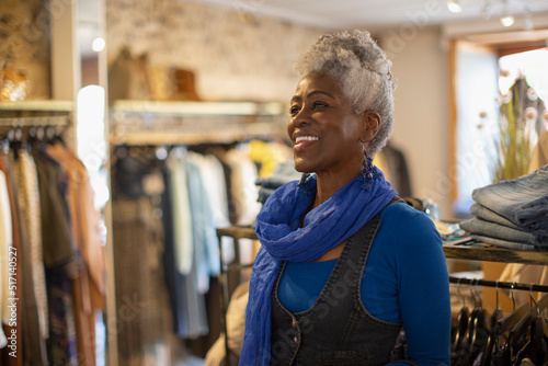 Happy female shop owner in blue scarf in clothing boutique photo