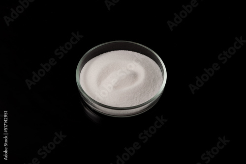 Sodium chlorate. White crystalline powder in a petri dish on a dark background. Chemical inorganic compound. Hygroscopic, readily soluble in water photo