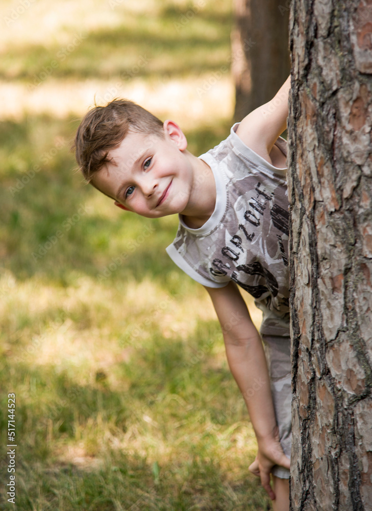 portrait of smiling happy child in forest near tree