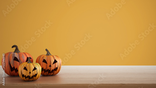 Halloween carved pumpkins on wooden table isolated on yellow colored background. Halloween backdrop with copy space for text. Autumn decoration