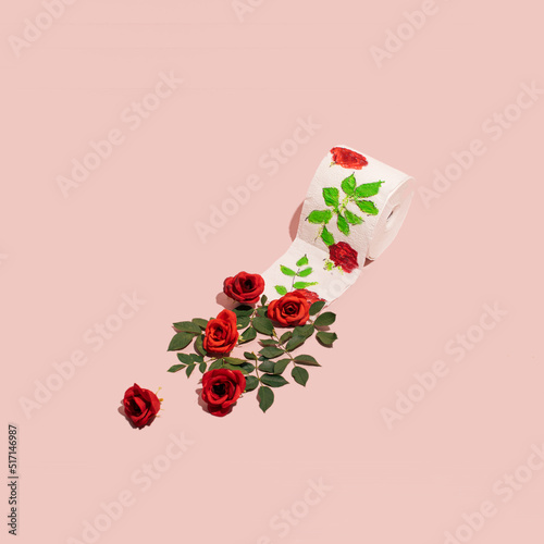 Toilet paper roll, creative floral layout on pastel pink background. Everyday essentials.