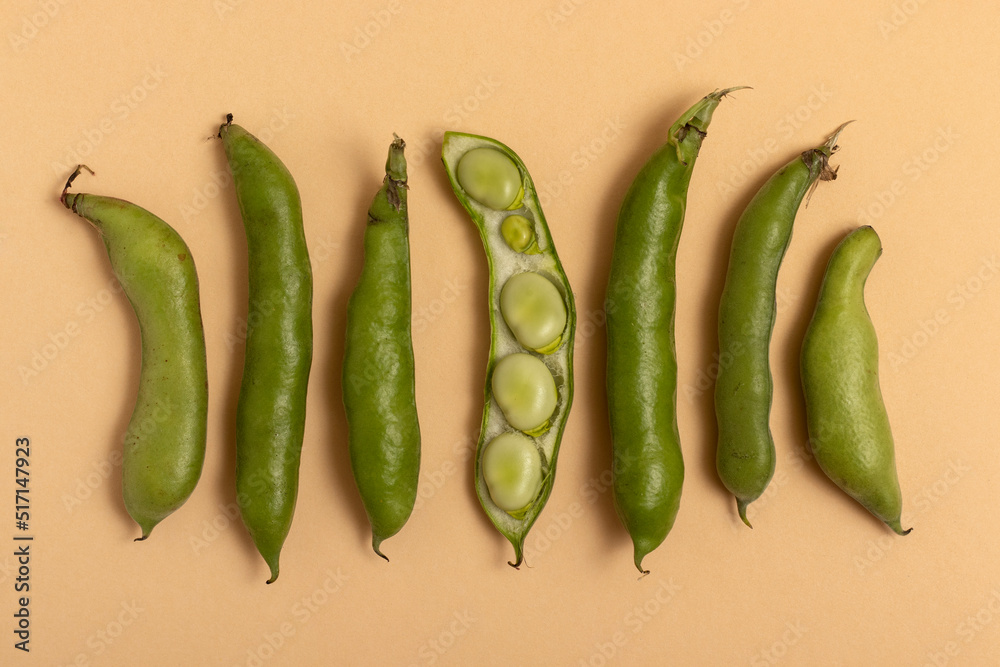 Broad beans in the pod on a beige background. Top view. Broad beans in the pod on a beige background. Top view.
