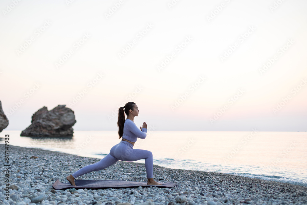 Young woman practice yoga and meditation near the sea at sunrise, healthy lifestyle concept. Warrior pose Young woman practice yoga and meditation near the sea at sunrise, healthy lifestyle concept. Warrior pose
