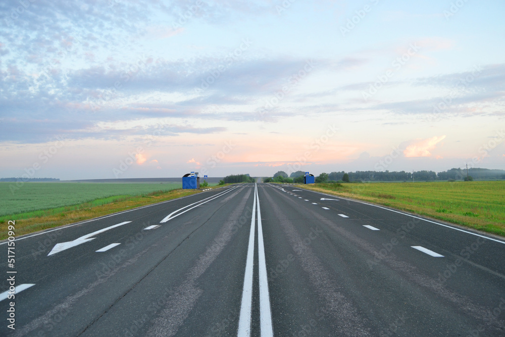 Fototapeta premium An empty paved road at dawn in a field