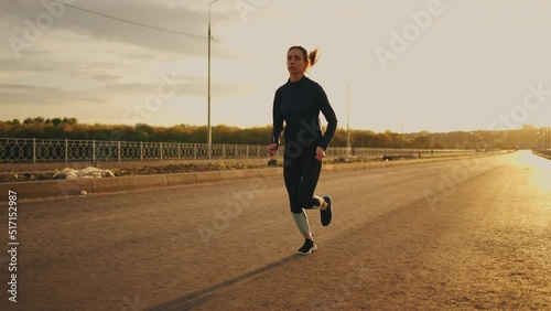 yougn woman in sportswear is jogging in sunrise or sunset, healthy lifestyle of modern youth photo