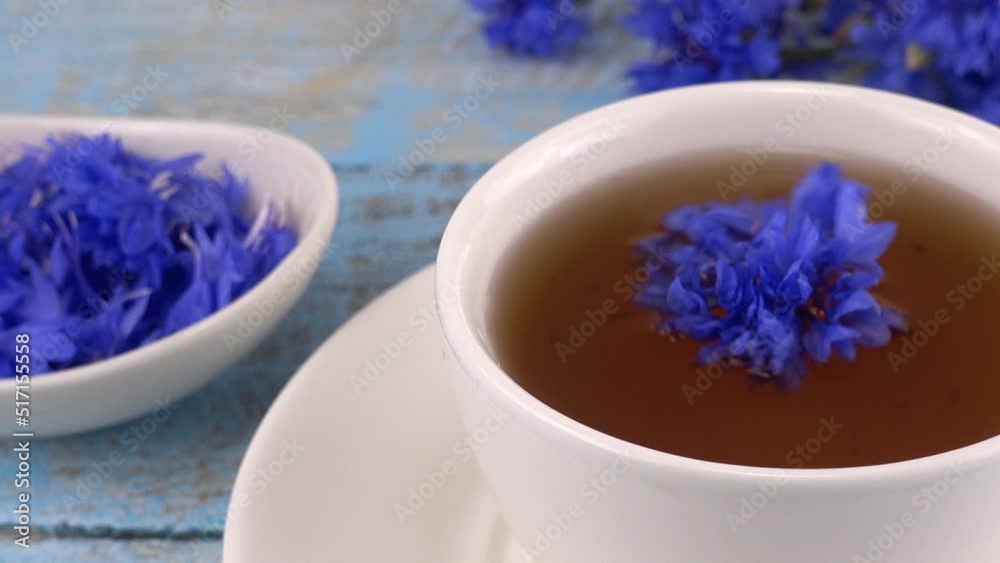 Composition with knapweeds flowers in white and blue colors on vintage light blue wooden tabletop. Brewing a tisanes from knapweeds flowers in white cup. Composition with knapweeds flowers in white and blue colors on vintage light blue wooden tabletop. Brewing a tisanes from knapweeds flowers in white cup.