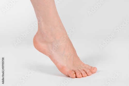 Barefoot and legs isolated on white background. Closeup shot of healthy beautiful female feet. Health and beauty concept. Side view of human foot ream with neutral manicure or pedicure. Sole of foot. photo