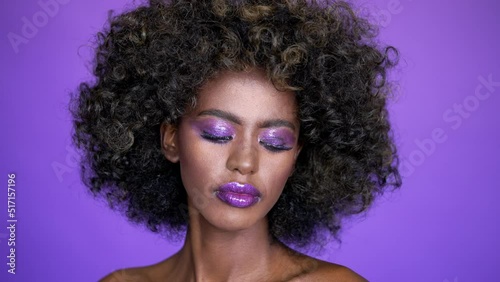 Portrait of beautiful african american female model with afro hair and glowing purple makeup photo