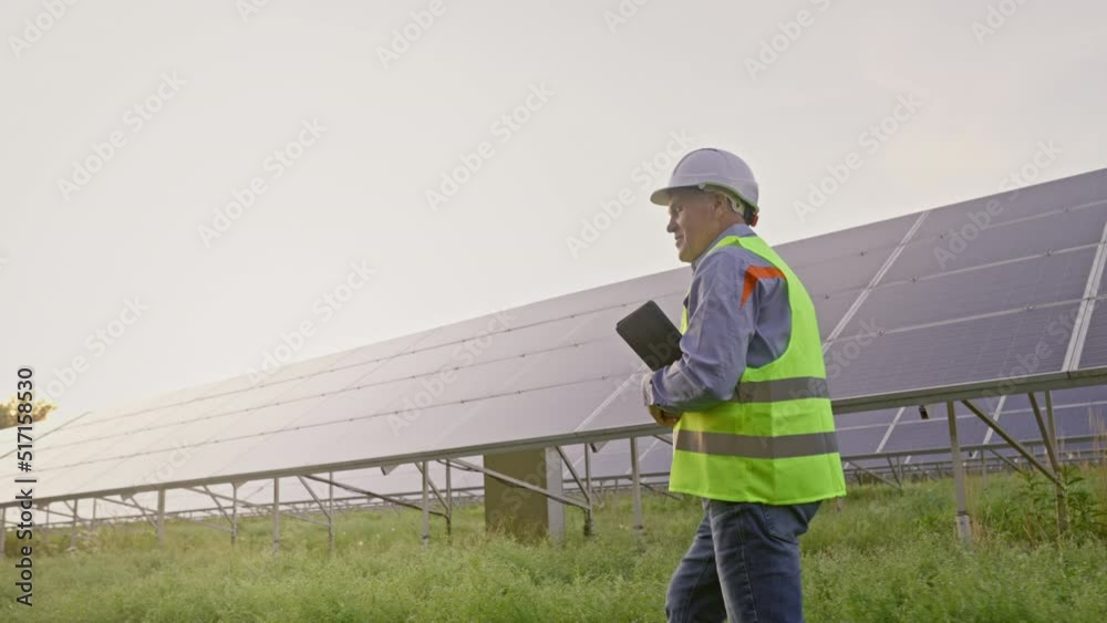 Mature solar energy specialist walking at a solar power facility Mature solar energy specialist walking at a solar power facility