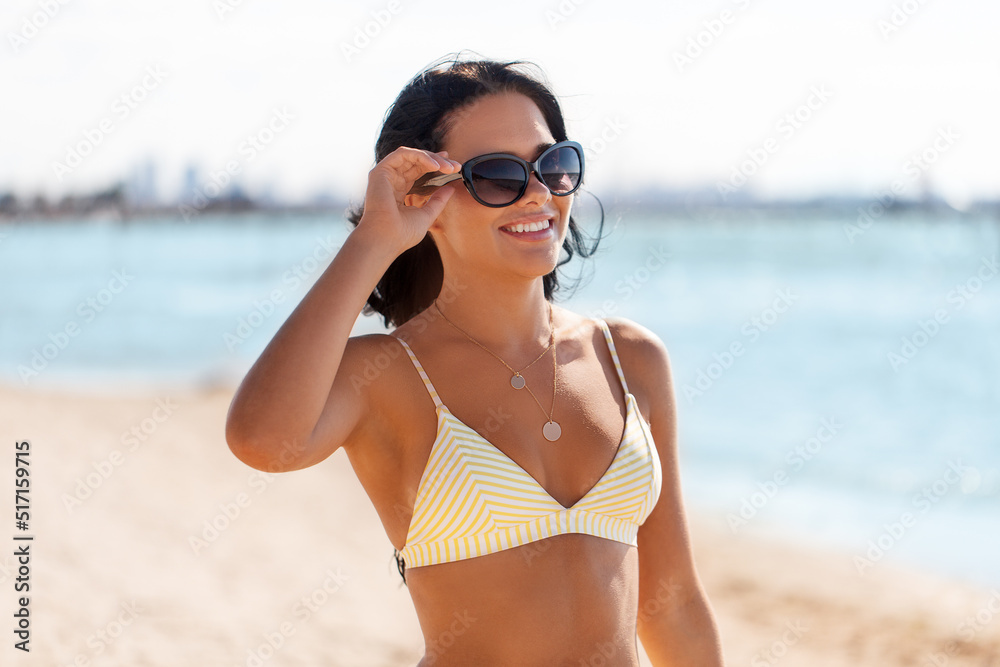 people, summer and swimwear concept - happy smiling young woman in bikini swimsuit and sunglasses on beach people, summer and swimwear concept - happy smiling young woman in bikini swimsuit and sunglasses on beach