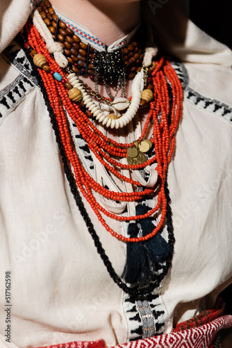 cropped view of ukrainian woman in traditional clothing with ornament and red beads.