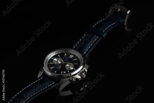 Studio shot of a blue fancy luxury unbranded Men watch on the black background. Stainless steel man's wrist watch with blue leather strap.