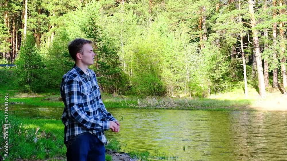 A man throws stones into the river and makes a wish. Fun in nature. Happy man in nature. Throwing stones into the river. A man throws stones into the river and makes a wish. Fun in nature. Happy man in nature. Throwing stones into the river.