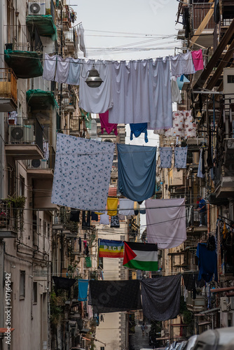 Laundry and flags hanging on clotheslines above the narrow street in the Historic Centre of Naples, Italy. © OKemppainen