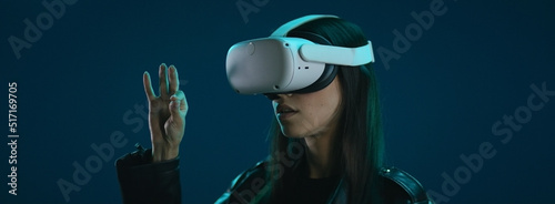 CU Portrait of Hispanic female using her VR metaverse headset against blue background photo