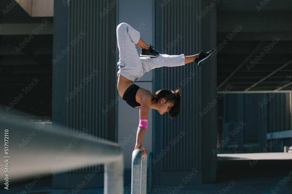 Fotografie Sportswoman doing handstand in city