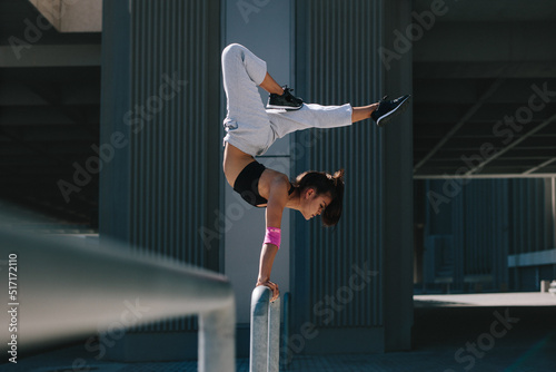 Obraz na plátně Sportswoman doing handstand in city