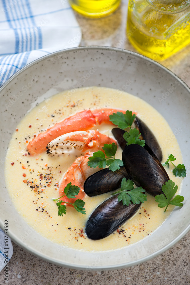 Close-up of cream-soup with mussels and kamchatka crab claws served in a beige plate, vertical shot Close-up of cream-soup with mussels and kamchatka crab claws served in a beige plate, vertical shot