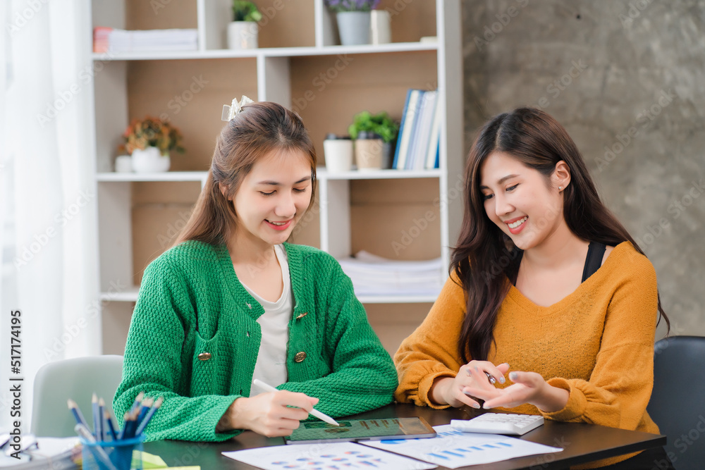 Two beautiful young asian businesswoman working together using digital tablet at office
