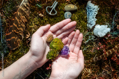 Space with feathers and crystals in the forest. Alternative medicine or esoteric background. Female hands holding amethyst crystal. photo