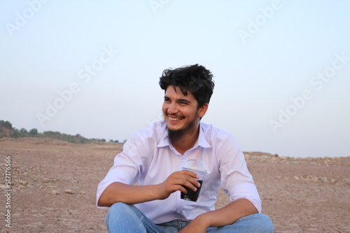Man enjoying his drink on river side dry land sitting with glass of juice in happy mood summer photography