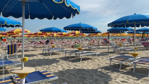 Windy beach umbrellas under a sunny and cloudy sky