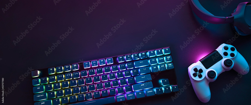 Top down view of colorful illuminated gaming accessories laying on table. Professional computer game playing, esports business and online world concept - obrazy, fototapety, plakaty 