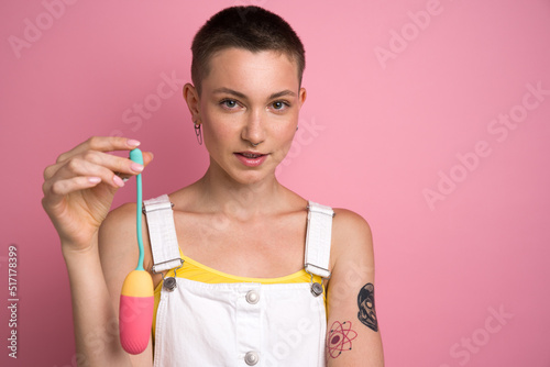 Short haired woman holding colourful vaginal egg and looking attentively to the camera