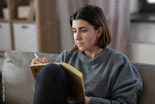 stress, mental health and depression concept - sad crying woman with diary sitting on sofa at home © Syda Productions
