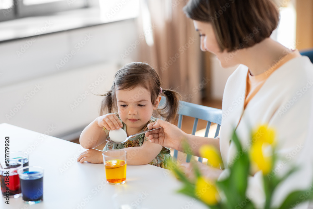 holidays, family and people concept - happy mother and little baby daughter dyeing easter eggs with colors at home holidays, family and people concept - happy mother and little baby daughter dyeing easter eggs with colors at home