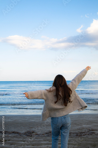 Young woman from behind is running at the beach to the sea in Larnaca, Cyprus