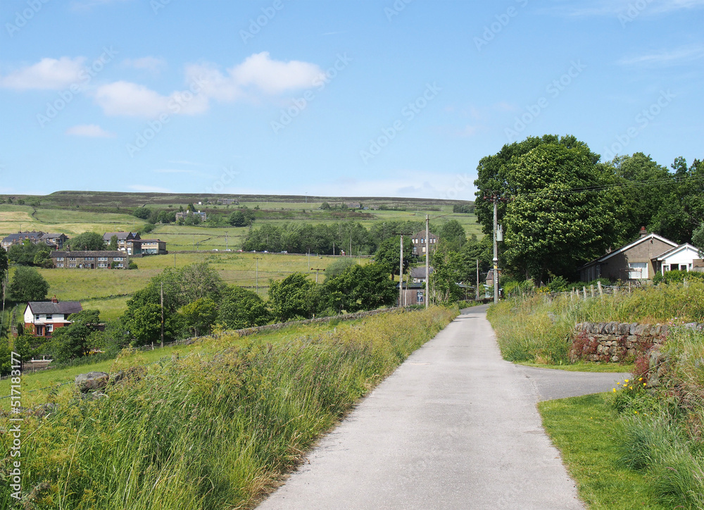 narrow country lane with the village of wadworth and hillside fields near hebden bridge in calderdale west yorkshire