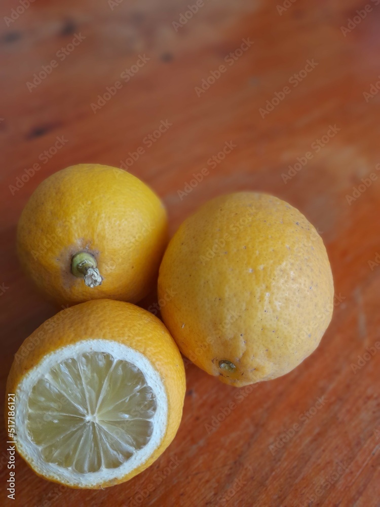 Grupo de limones o limas cítricos de dieta sana amarilla madura con corte que muestra la pulpa y la piel texturizada, forman un diseño natural original con fondo de mesa marrón 