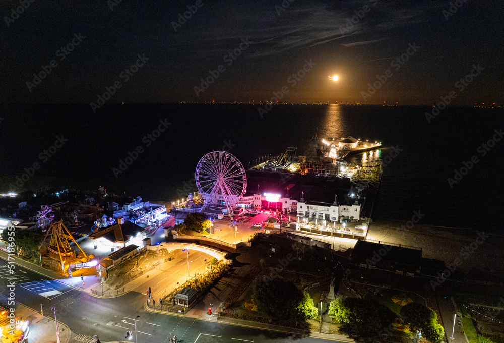 Clacton Pier at night with full moon rising over the sea.