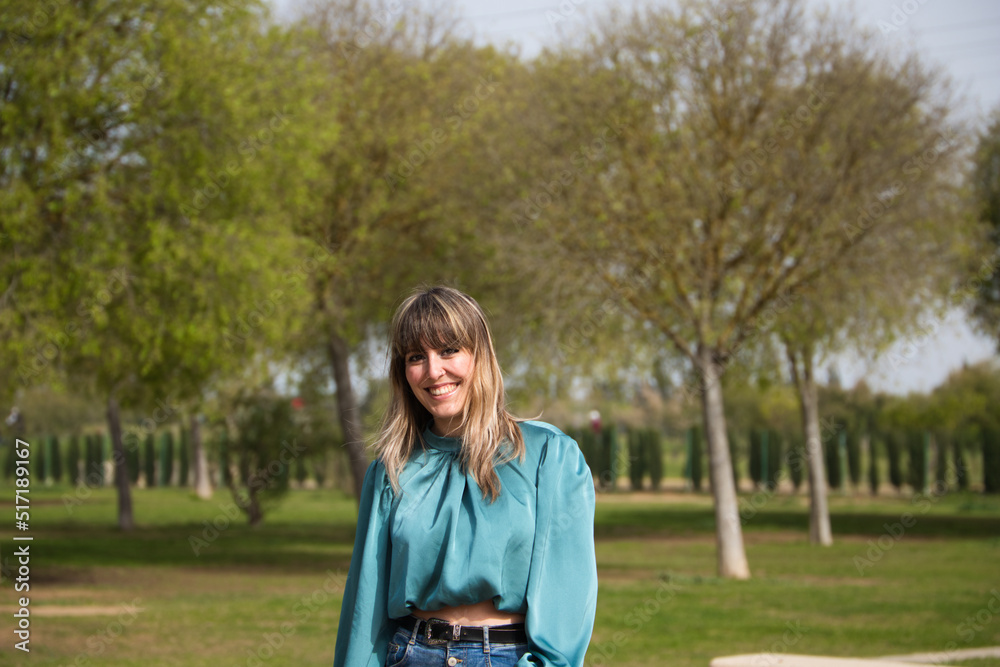 beautiful young blonde woman dressed in jeans and boots is walking in the park and is having her photo taken while enjoying the sunny spring day in europe. Holiday and free time concept. beautiful young blonde woman dressed in jeans and boots is walking in the park and is having her photo taken while enjoying the sunny spring day in europe. Holiday and free time concept.