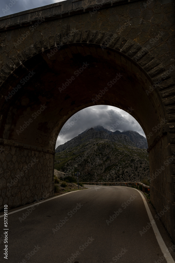 Krajobraz górski w szary pochmurny dzień. Tunel prowadzący do drogi Sa Calobra, Majorka Hiszpania. - obrazy, fototapety, plakaty 