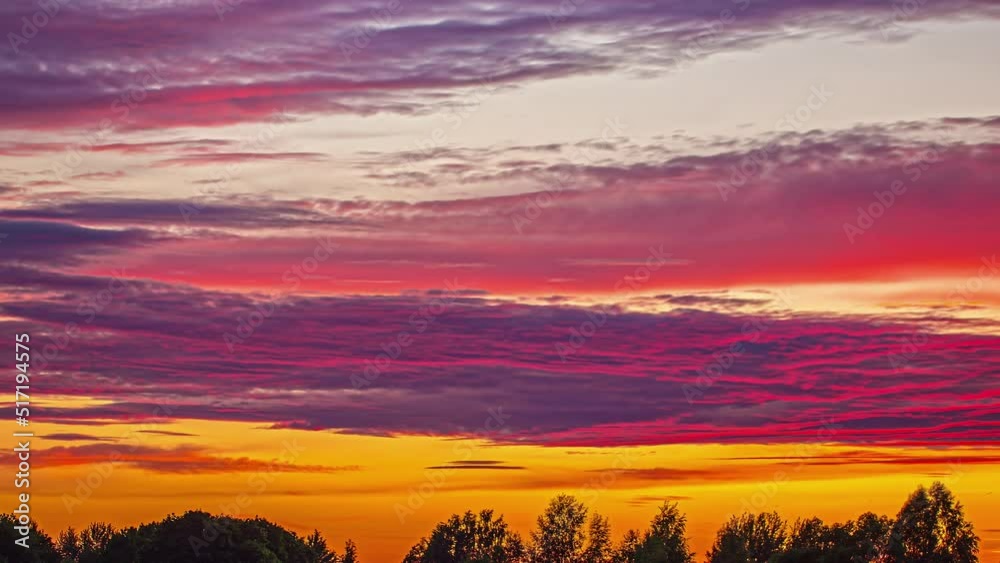 Fiery Sky With Dusky Gray Cloudscape Moving Over Trees In Silhouettes. Timelapse Fiery Sky With Dusky Gray Cloudscape Moving Over Trees In Silhouettes. Timelapse