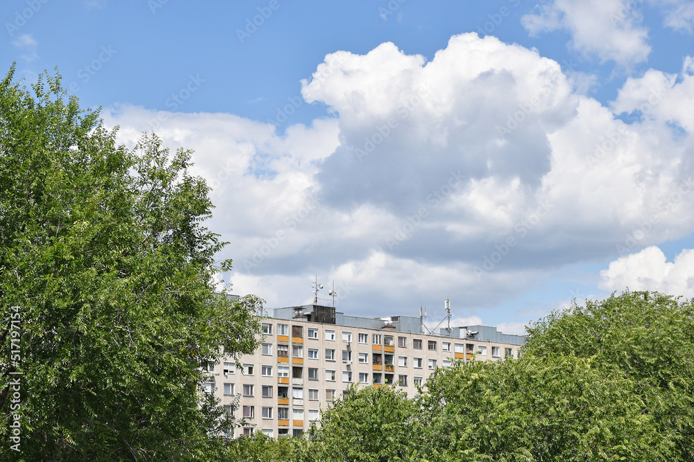 Apartment buildings behind trees under clouds