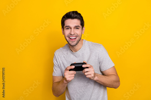 Photo of nice brunet millennial guy playstation wear grey t-shirt isolated on yellow color background © deagreez