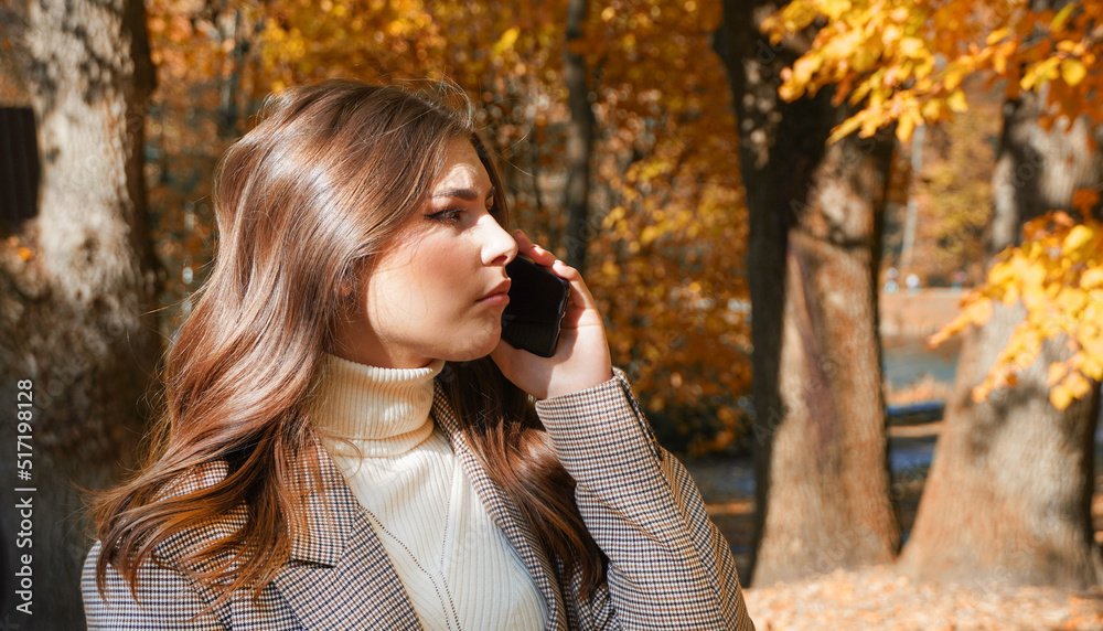 Happy young woman using cell phone in autumn park. Cute girl using smartphone in park with autumn colors. Happy young woman using cell phone in autumn park. Cute girl using smartphone in park with autumn colors.