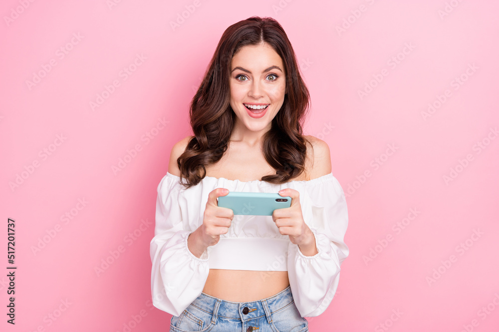 Photo of charming cheerful overjoyed girl addicted to videogames using telephone isolated on pink color background