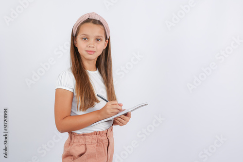 girl looking at the camera and writing in a notebook. High quality photo
