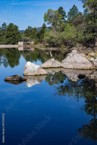 View of Goldwater Lake Dam in Prescott Arizona with bright blue sky, reflections of trees, and a crane on the rock photo