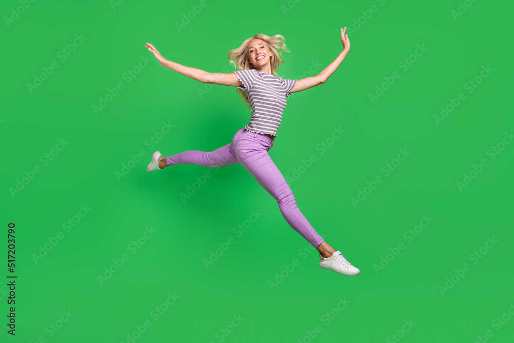 Full body portrait of sporty excited cheerful girl jumping rush hurry isolated on green color background