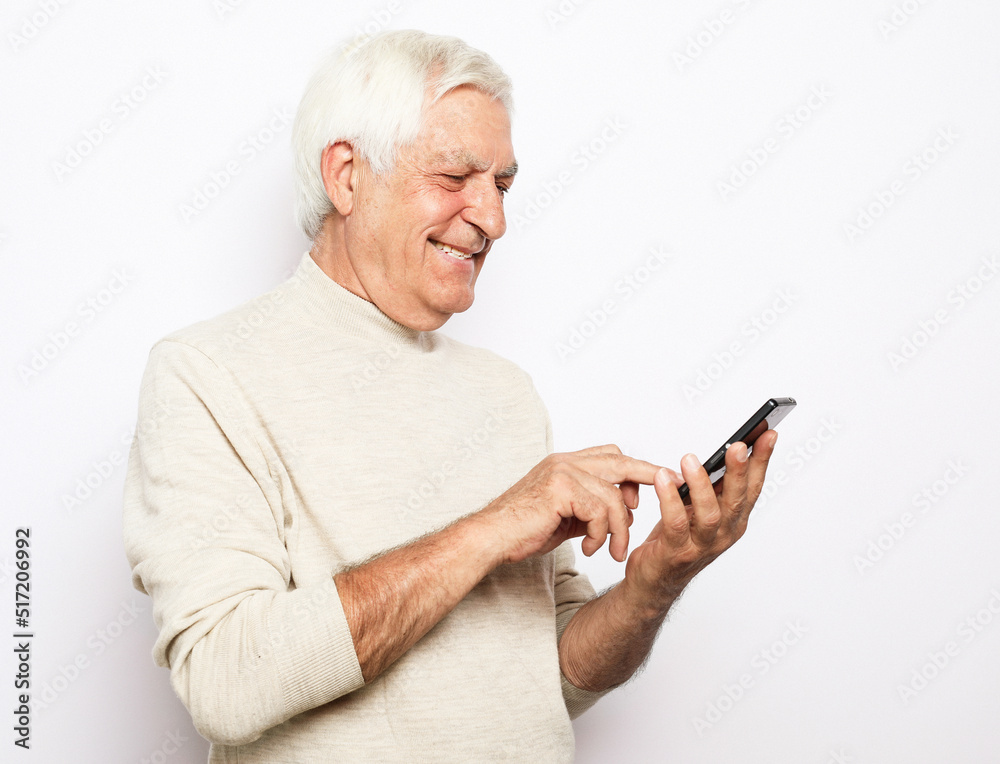 Portrait of senior man who is messaging on smartphone over white background, close up Portrait of senior man who is messaging on smartphone over white background, close up