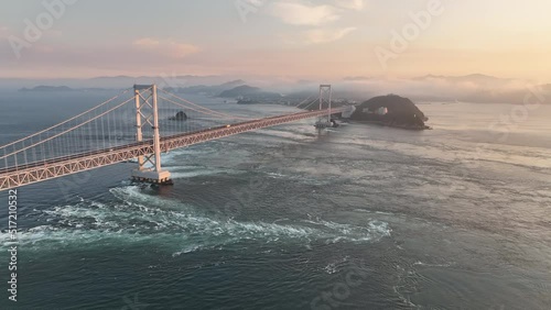 Aerial move over whirlpools and eddies under Naruto suspension bridge at sunset photo