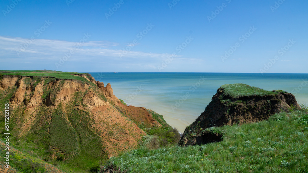 Ruined clay slope by the sea. Cracked clay cliff on the coast. A crumbling and cracked clay wall on the beach.