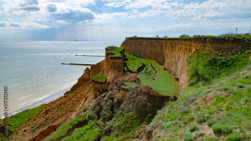 Ruined clay slope by the sea. Cracked clay cliff on the coast. A crumbling and cracked clay wall on the beach.