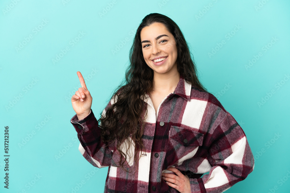 Young caucasian woman isolated on blue background showing and lifting a finger in sign of the best Young caucasian woman isolated on blue background showing and lifting a finger in sign of the best