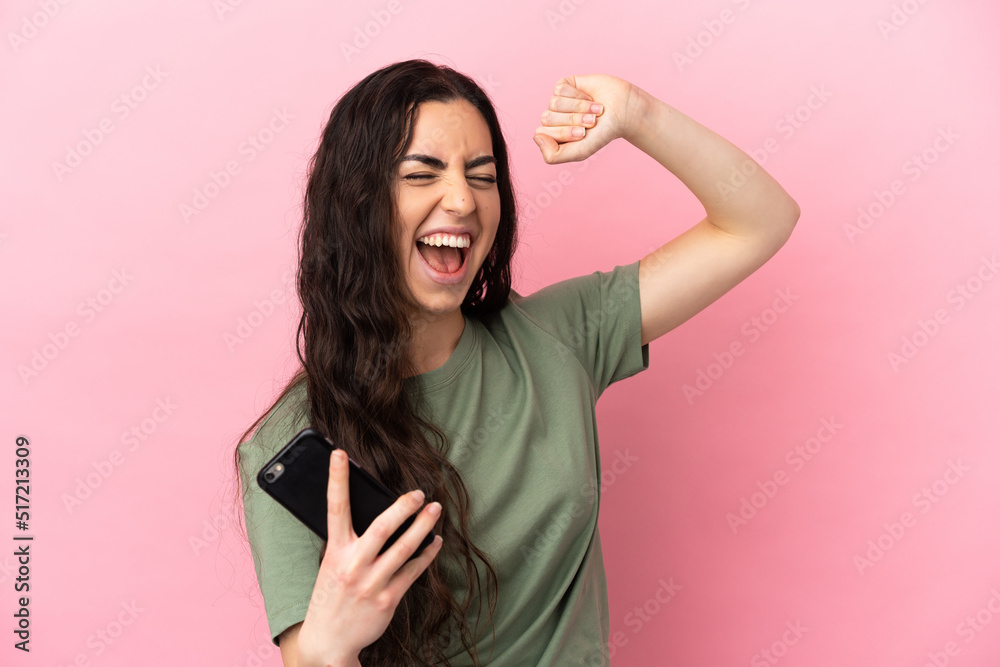 Young caucasian woman isolated on pink background using mobile phone and singing Young caucasian woman isolated on pink background using mobile phone and singing